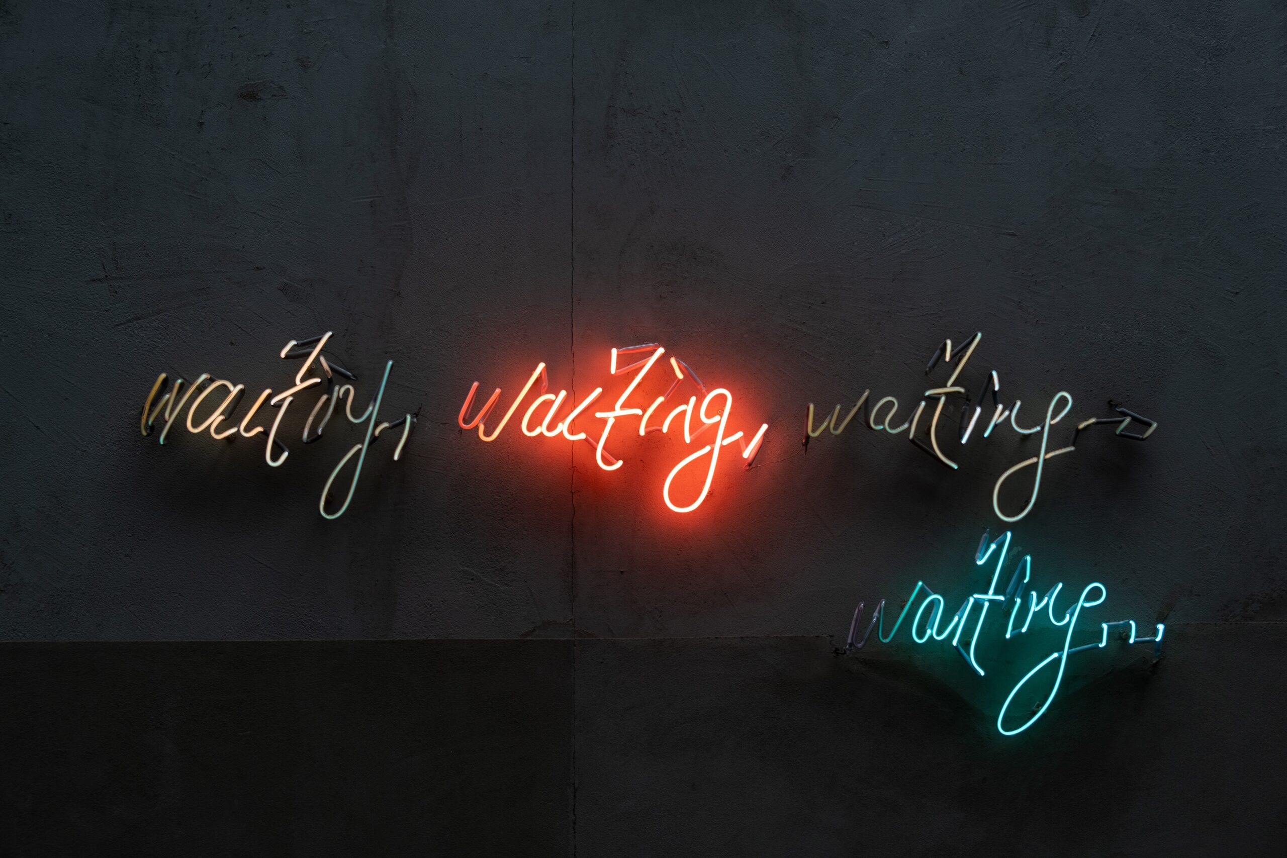 Image of a neon sign saying "waiting, waiting, waiting, waiting. . ."